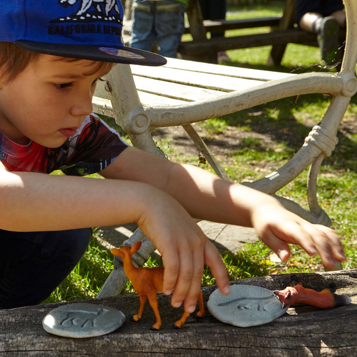 malý chlapec sa hrá s fugúrkou a kamennou stopou líšky a srnky